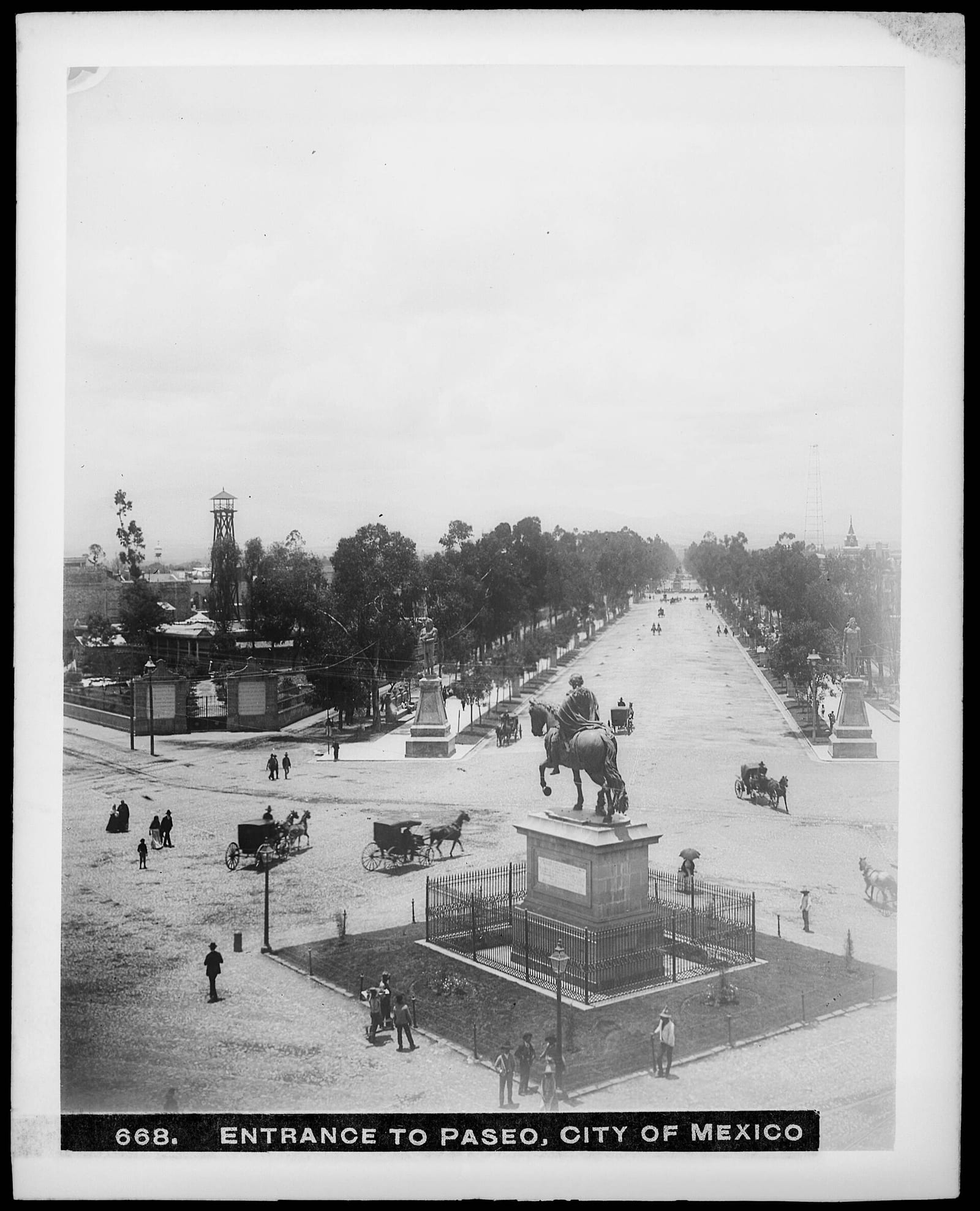 Vista elevada de la entrada del Paseo de la Reforma con la estatua ecuestre de Carlos IV y carruajes.
